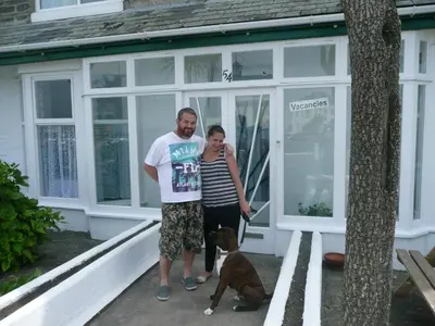 a man and woman standing outside of a house with a dog at The Lyncroft in Newquay
