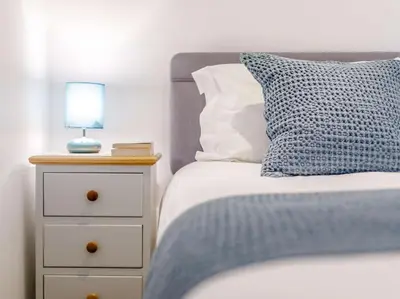 a bed with a blue pillow and a lamp on a night stand at 2 Bed in St. Austell oc-79594 in Saint Stephen