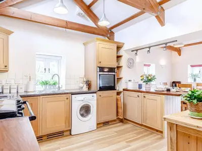 a kitchen with wooden cabinets and a washer and dryer at 2 Bed in St. Austell oc-79594 in Saint Stephen