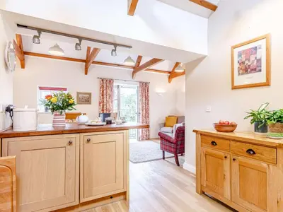 a kitchen with wooden cabinets and a living room at 2 Bed in St. Austell oc-79594 in Saint Stephen