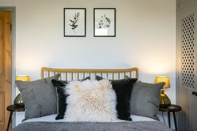 a bed with black and white pillows and two pictures at Harewood, Port Isaac Bay Holidays in Port Isaac