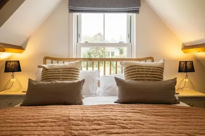 a bedroom with a bed with pillows and a window at Harewood, Port Isaac Bay Holidays in Port Isaac