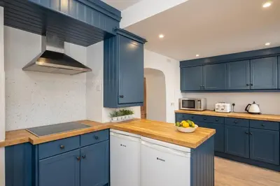 a kitchen with blue cabinets and a bowl of fruit on a counter at Harewood, Port Isaac Bay Holidays in Port Isaac