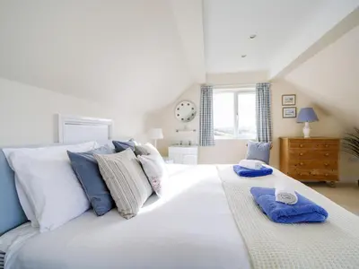 a bedroom with a large white bed with blue pillows at Trevarthian in Polzeath