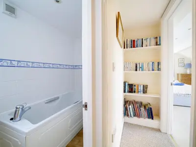 a bathroom with a tub and a book shelf with books at Trevarthian in Polzeath