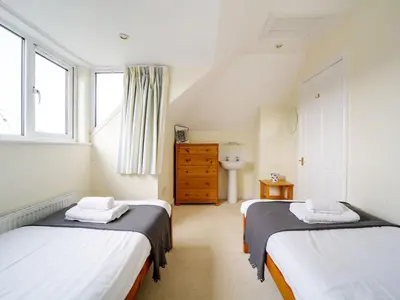 a bedroom with two beds and a sink in it at Trevarthian in Polzeath