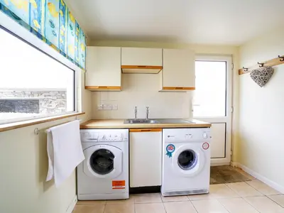 a kitchen with a washing machine and a sink at Trevarthian in Polzeath