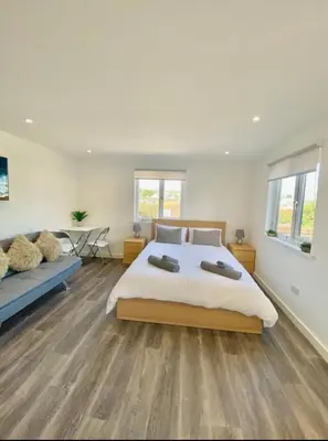 a white bedroom with a large bed and a table at Casa Studio in St Ives