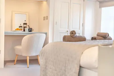 a bedroom with a bed with a chair and a mirror at 4 Bed in St. Merryn oc-e28379 in St Merryn