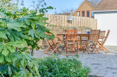 a patio with chairs and a table and a fence at 4 Bed in St. Merryn oc-e28379 in St Merryn
