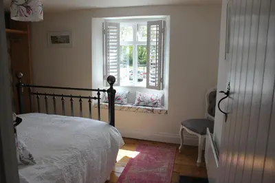 a bedroom with a bed and a window with a chair at Lil' Nauti in Pentewan