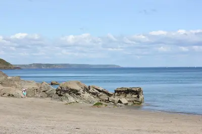 a person walking on a beach near the water at Lil' Nauti in Pentewan