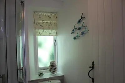 a bathroom with a window with birds on the wall at Lil' Nauti in Pentewan