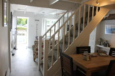 a staircase in a house with a wooden table and a dining room at Lil' Nauti in Pentewan