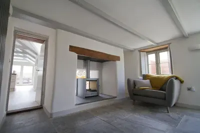 a living room with a chair and a fireplace at Barnwell Cottage *Stunning Cornish Cottage* Oozing Charm + Comfort in Cubert