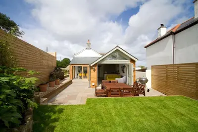 a patio with a table and chairs in a yard at Barnwell Cottage *Stunning Cornish Cottage* Oozing Charm + Comfort in Cubert