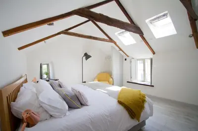 a bedroom with a bed with white sheets and pillows at Barnwell Cottage *Stunning Cornish Cottage* Oozing Charm + Comfort in Cubert