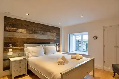 a bedroom with a large bed with a wooden wall at Finest Retreats - Dingles Cottage in Philleigh