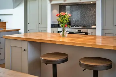 a kitchen with a counter with two stools and a vase with flowers at Finest Retreats - Dingles Cottage in Philleigh