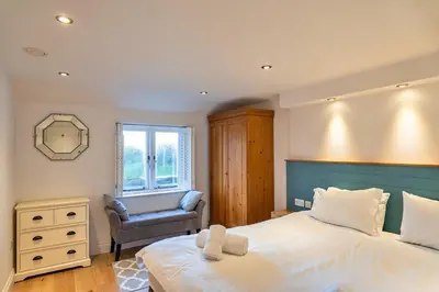 a bedroom with a large bed and a chair at Finest Retreats - Dingles Cottage in Philleigh