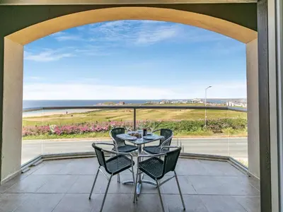 a table and chairs on a balcony with a view of the ocean at The Vista in Newquay
