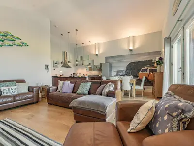 a living room with brown couches and a kitchen at The Vista in Newquay