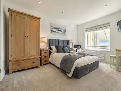 a bedroom with a large bed and a wooden cabinet at The Vista in Newquay