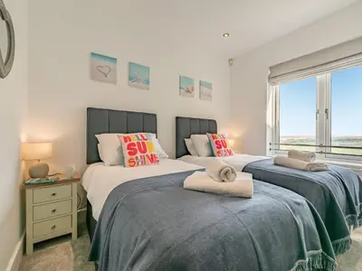 two beds in a bedroom with a window at The Vista in Newquay