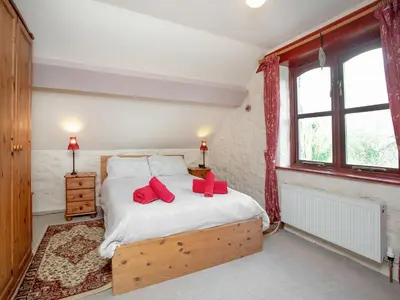 a bedroom with a bed with red pillows on it at Bulls Cottage in Bodmin