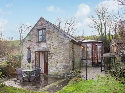 a stone house with a table and chairs in front of it at Bulls Cottage in Bodmin