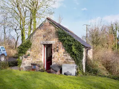 a small stone house with a red door at Bulls Cottage in Bodmin