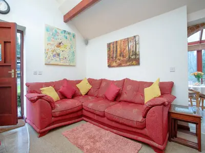a red couch with yellow pillows in a living room at Bulls Cottage in Bodmin