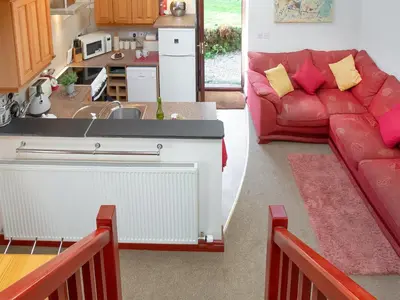 a kitchen and a living room with a red couch at Bulls Cottage in Bodmin
