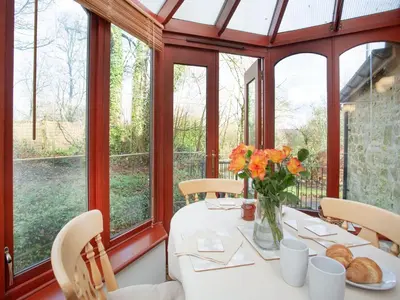 a dining room with a table with a vase of flowers at Bulls Cottage in Bodmin