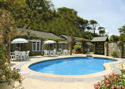 a swimming pool with chairs and a house at 11 Granite Henge in Pelynt