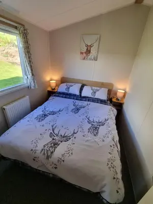 a bedroom with a bed with a blue and white comforter at Seaside View Caravan in Polperro in Looe