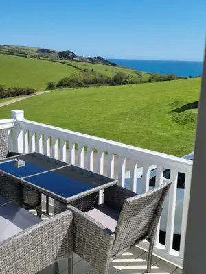 a patio with a table and chairs on a balcony at Seaside View Caravan in Polperro in Looe