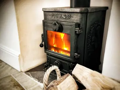 a stove with a fire in it in a room at Ebb Tide - Fisherman's Cottage in Gorran Haven