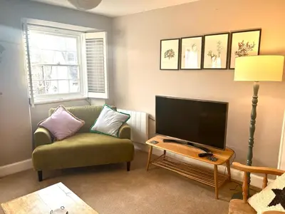 a living room with a green couch and a flat screen tv at Ebb Tide - Fisherman's Cottage in Gorran Haven