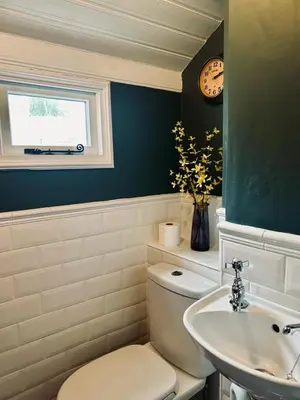 a bathroom with a toilet and a sink and a clock at Ebb Tide - Fisherman's Cottage in Gorran Haven