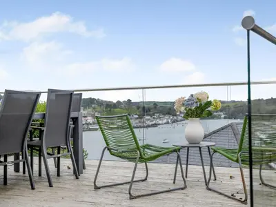 a balcony with chairs and a table with a vase of flowers at 4 Bed in Polruan oc-pc044 in Fowey