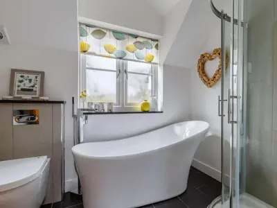 a white bath tub in a bathroom with a window at 5 Bed in Redruth oc-65745 in Gwennap