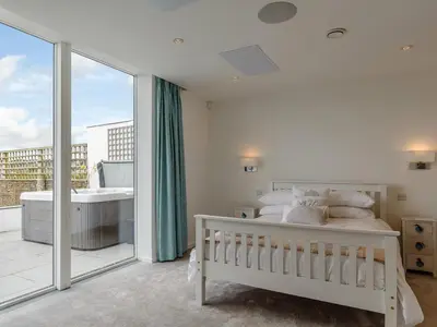 a white bedroom with a bed and a balcony at 5 Bed in Fowey oc-77657 in Polruan