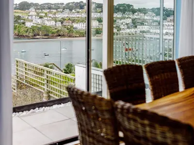 a room with a table and chairs and a view of the water at 5 Bed in Fowey oc-77657 in Polruan