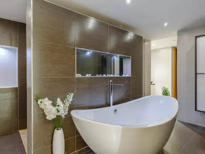 a bathroom with a large tub and a vase of flowers at 5 Bed in Fowey oc-77657 in Polruan