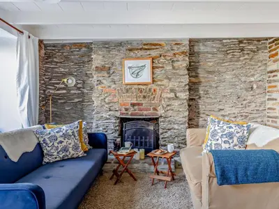 a living room with a blue couch and a stone wall at 3 Bed in Polruan oc-83821 in Fowey