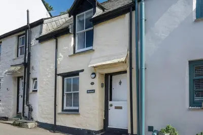 a white house with a door in a street at Homestead in Port Isaac