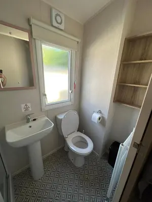 a bathroom with a sink and a toilet and a window at CaravanSleeps4-Beachfront-Garden-Patio in Newquay