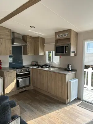 a kitchen with wooden cabinets and a stove top oven at CaravanSleeps4-Beachfront-Garden-Patio in Newquay