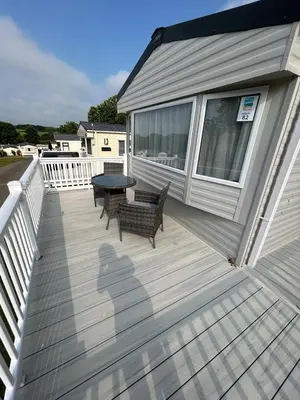 a wooden deck with benches and a table on a house at CaravanSleeps4-Beachfront-Garden-Patio in Newquay